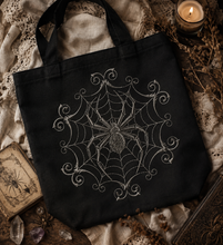Load image into Gallery viewer, Midnight Lace Spider embroidered on a black tote bag, featuring an ornate symmetrical spider web with elegant Victorian Gothic details, perfect for dark academia and Halloween style.